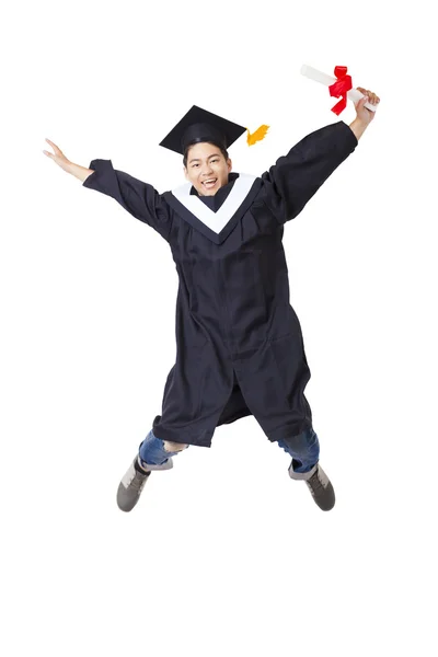 Felice studente in vestaglia laureato saltando contro sfondo bianco — Foto Stock