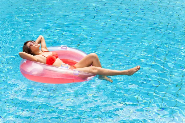 Jovem mulher relaxante na piscina — Fotografia de Stock