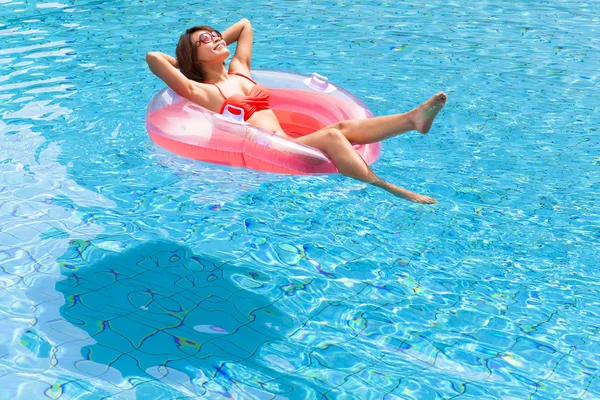 Yüzme havuzunda dinlenen genç bir kadın.