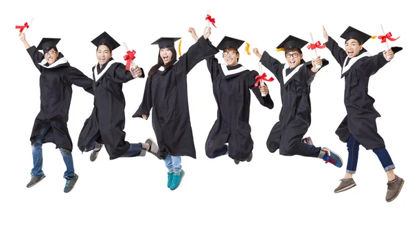 Feliz grupo de estudiantes en bata de graduado saltando juntos —  Fotos de Stock