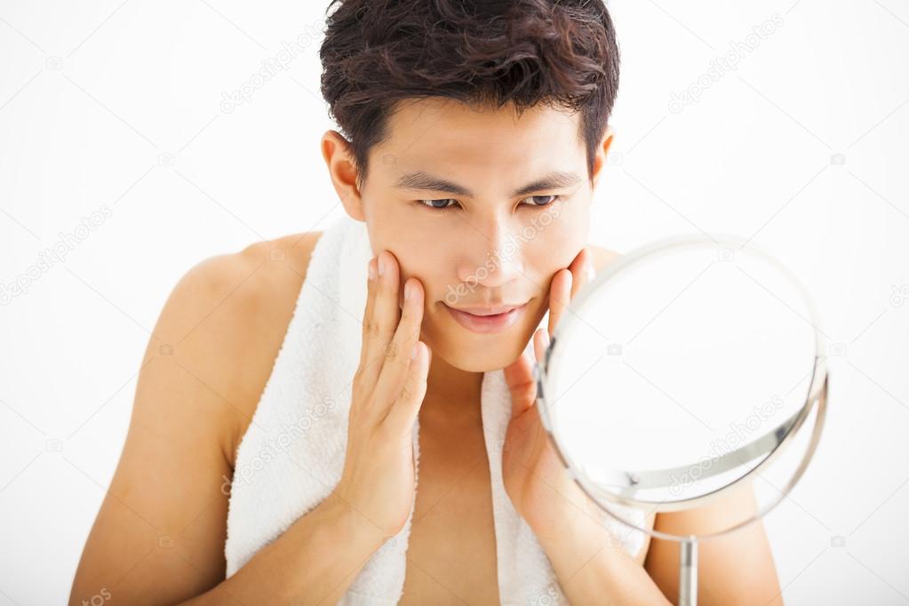 Young man touching his smooth face after shaving Stock Photo by