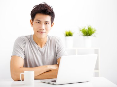 oturma odasında dizüstü kullanarak gülümseyen genç adam