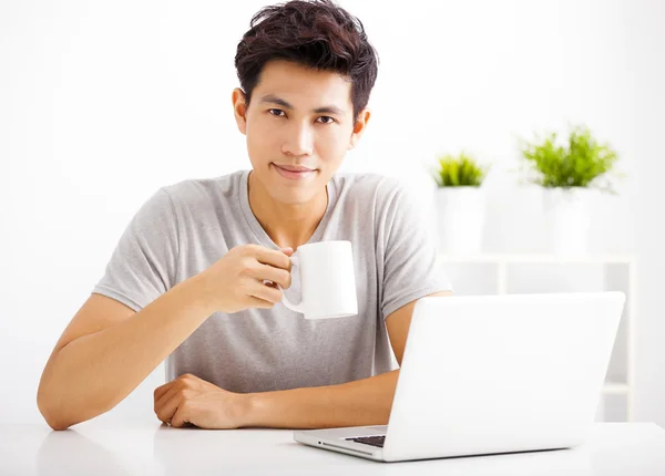 Sorridente giovane uomo utilizzando il computer portatile in soggiorno — Foto Stock