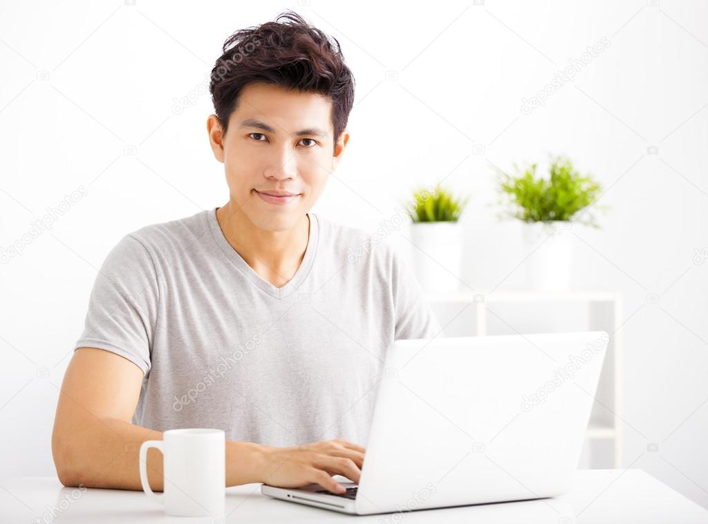 Smiling  young man using laptop in living room