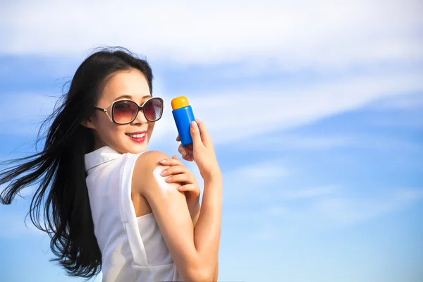 Junge Frau cremt sich mit Sonnenschutz ein — Stockfoto