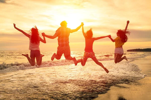 Groep gelukkige jongeren springen op het strand — Stockfoto
