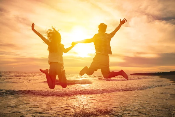 Jovem casal feliz pulando na praia — Fotografia de Stock