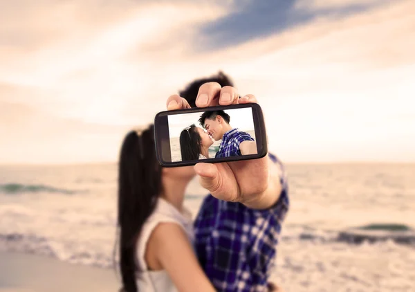 Par ta självporträtt bilder med smart telefon på stranden — Stockfoto