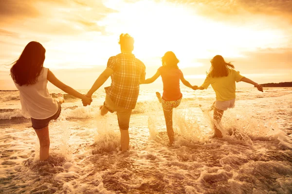 Groupe de jeunes gens heureux jouant sur la plage — Photo