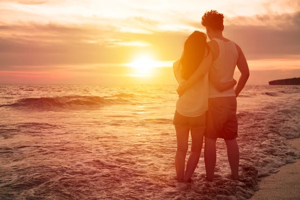 Young couple watching sunset on the beach ストック写真