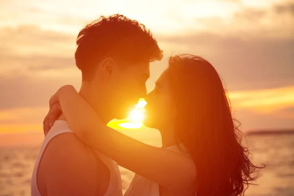 Ungt par kyssas i solnedgången på stranden — Stockfoto