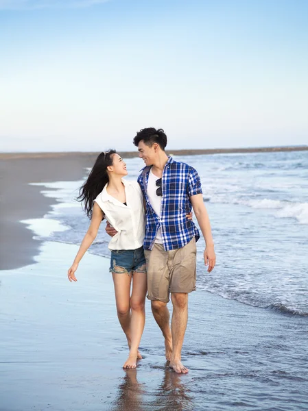 Joyeux jeune couple marchant sur la plage — Photo