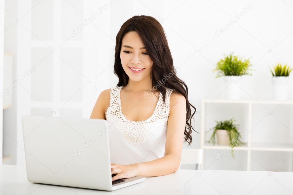 Happy pretty woman using laptop in living room