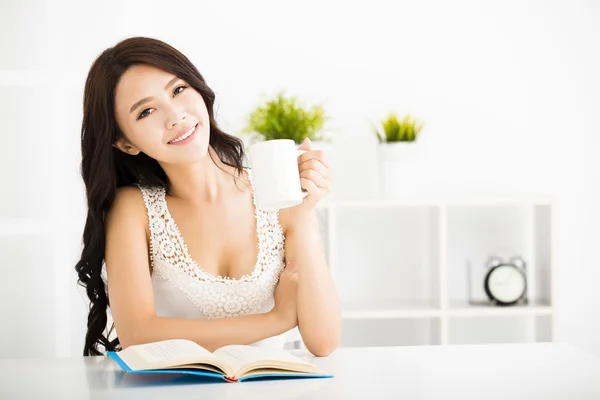 Felice giovane donna lettura libro in soggiorno — Foto Stock