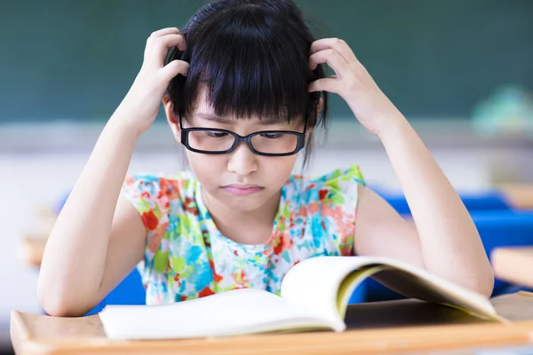 Niedergeschlagenes kleines Mädchen lernt im Klassenzimmer — Stockfoto