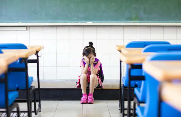 Benadrukken meisje zit en denken op de verdieping van de klas — Stockfoto