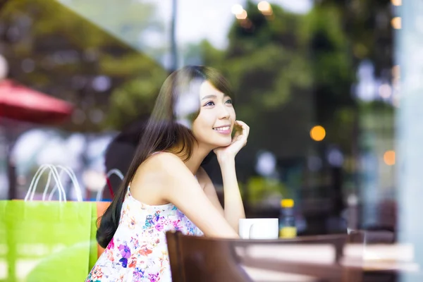 Souriant jeune femme pensant dans le café boutique — Photo