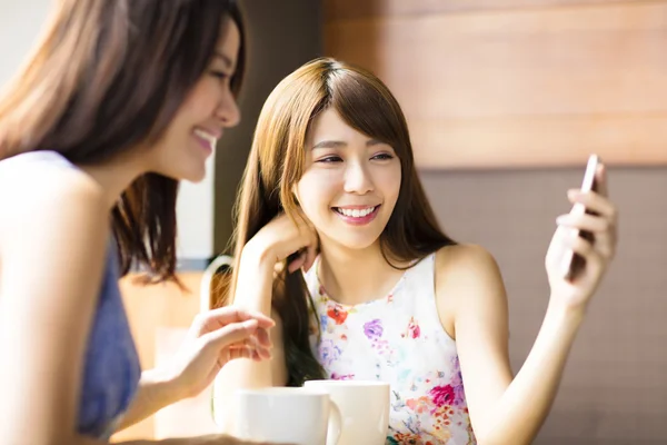 Gelukkig jonge vrouw kijken naar telefoon in koffie winkel — Stockfoto