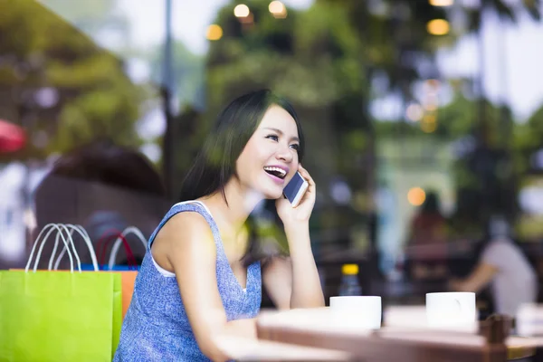Mosolygó fiatal nő beszél a telefonon a café üzlet — Stock Fotó