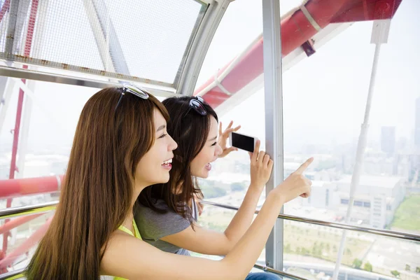 Happy girls taking photo in the ferris wheel — Stock Photo, Image