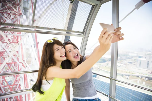 Mulheres felizes namoradas tomando uma selfie na roda gigante — Fotografia de Stock