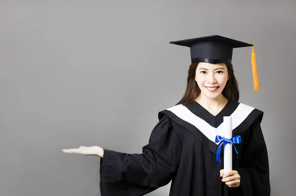 Beautiful young  graduate holding diploma with showing gesture — Stock Photo, Image