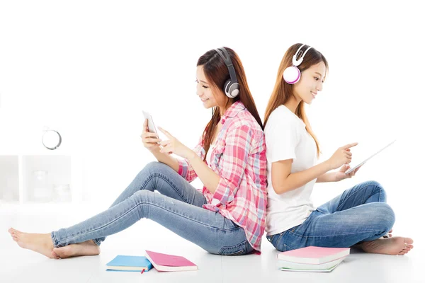 Twee gelukkige tiener studenten meisjes zittend op de vloer — Stockfoto