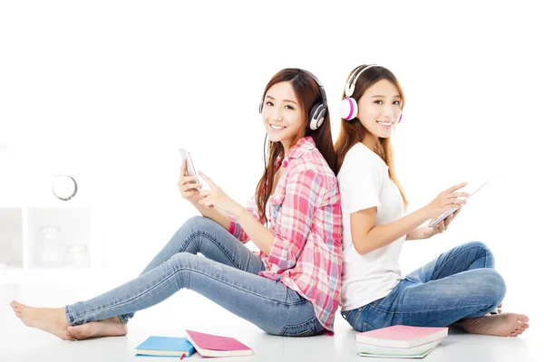 Twee gelukkige tiener studenten meisjes zittend op de vloer — Stockfoto