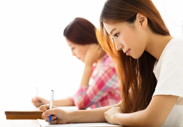 Joven estudiante con otros escribiendo notas en el aula — Foto de Stock