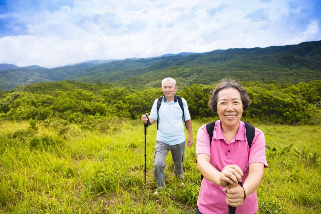 happy senior couple hiking on the mountain