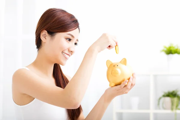 Happy young woman saving money in the piggy bank — Stock Photo, Image