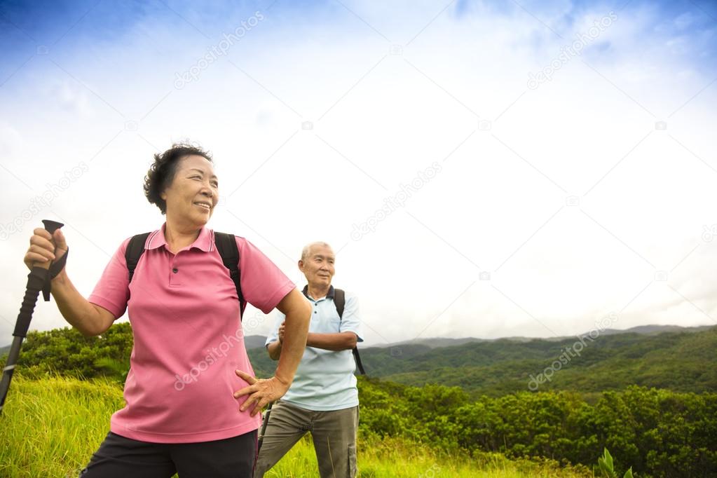 happy senior couple hiking on the mountain