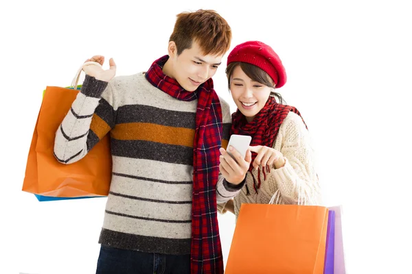 Happy couple shopping together and looking smart phone — Stock Photo, Image