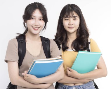 Not defteri ve sırt çantası taşıyan Asyalı kız öğrenciler.