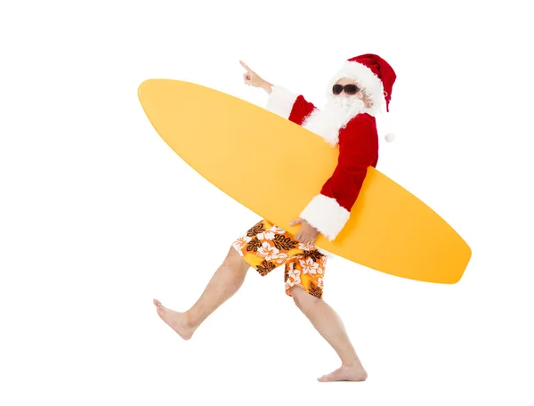 Happy Santa Claus holding surf board with pointing gesture — Stock Photo, Image