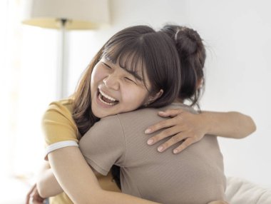 Mutlu Asyalı kızlar dostça kucaklaştılar. 