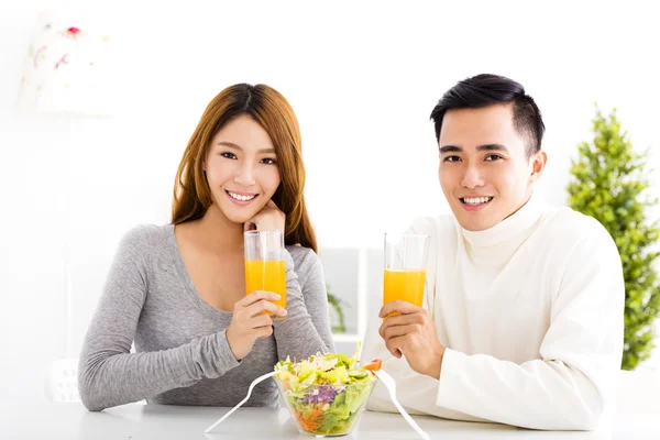 Junges lächelndes Paar trinkt Saft und gesundes Essen — Stockfoto