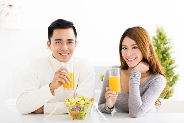 Joven pareja sonriente bebiendo jugo y comida saludable —  Fotos de Stock