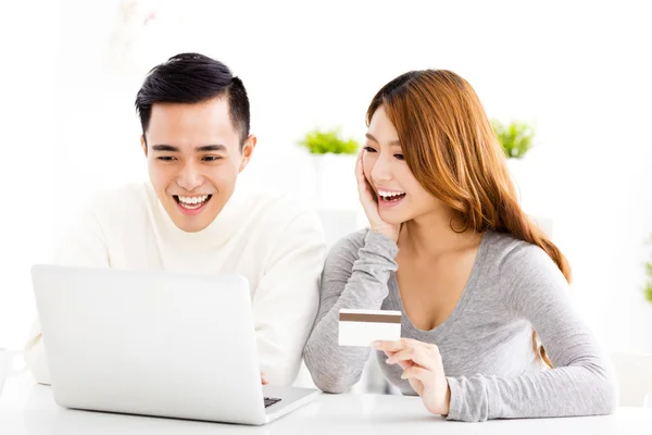 Heureux jeune couple avec carte de crédit et ordinateur portable — Photo