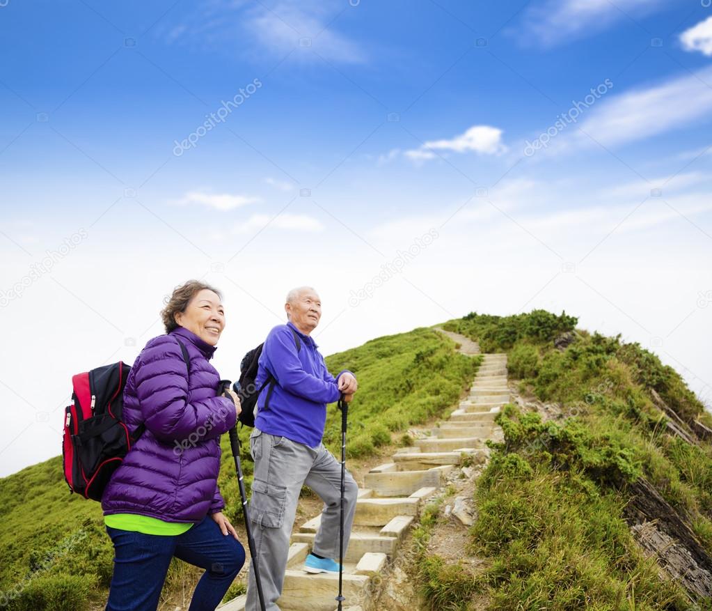 happy asian senior couple hiking on the mountain