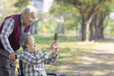 Asyalı yaşlı kadın cep telefonuyla kocasına bilgi paylaşıyor