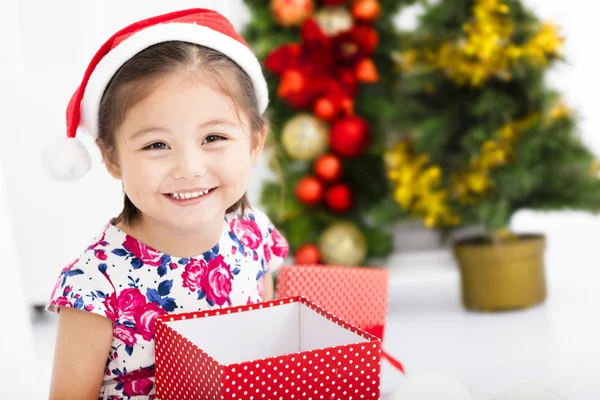 Noel Baba kırmızı şapka ve Noel hediyesi tutan mutlu küçük kız — Stok fotoğraf