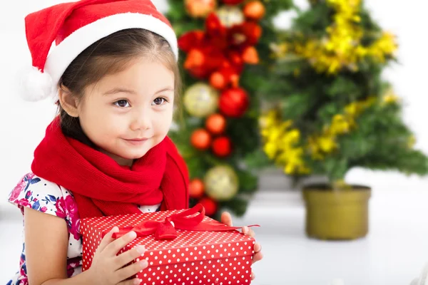 Lycklig liten flicka i Santa röd hatt och hålla julklapp — Stockfoto