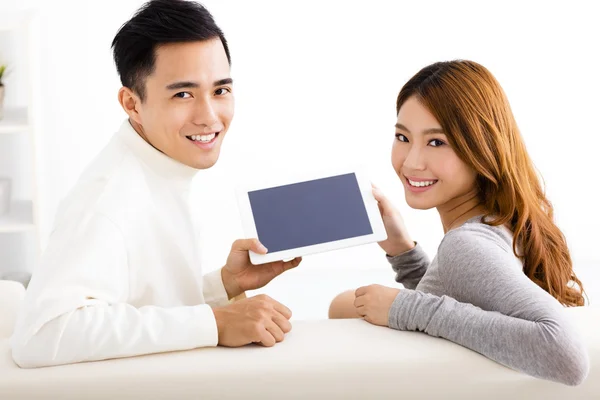 Šťastný mladý pár pomocí tabletu na pohovce — Stock fotografie