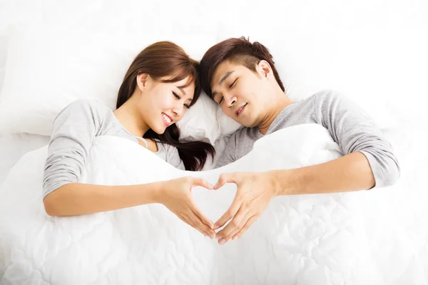Jovem feliz lindo casal deitado em uma cama — Fotografia de Stock