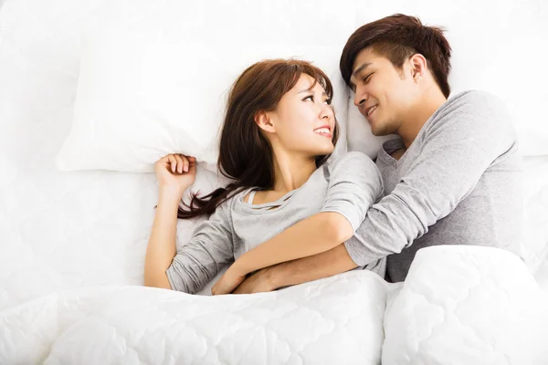 Jovem feliz lindo casal deitado em uma cama — Fotografia de Stock