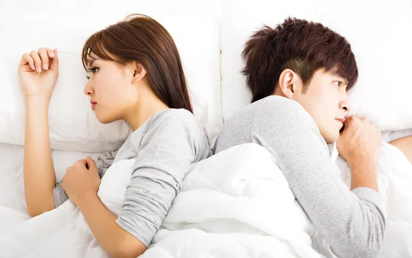 Casal jovem perturbado deitado lado a lado na cama — Fotografia de Stock