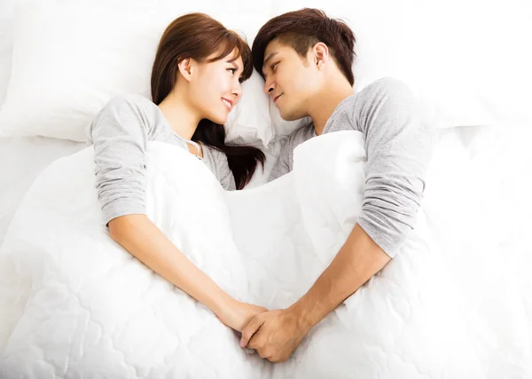 Glückliches junges schönes Paar liegt in einem Bett — Stockfoto