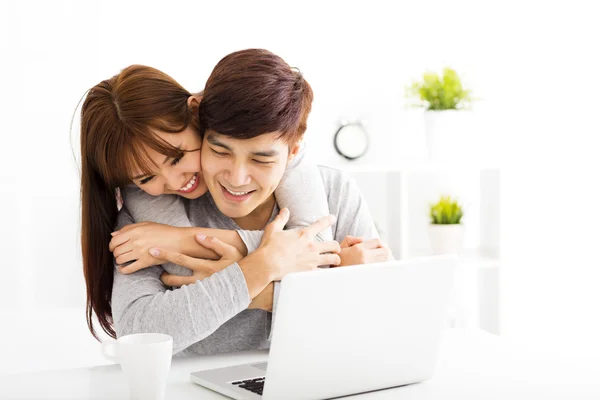 Feliz jovem lindo casal com laptop na sala de estar — Fotografia de Stock