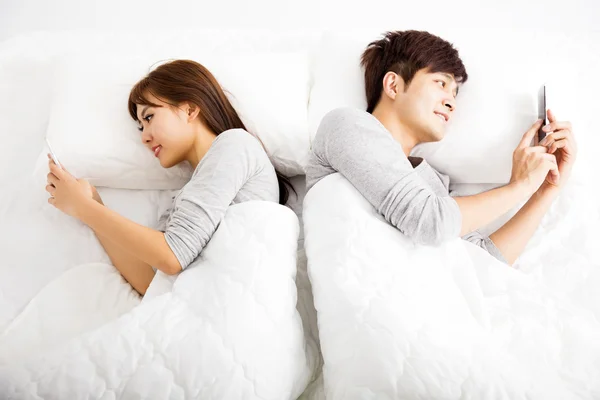 Happy young couple in a bed with smart phones — Stock Photo, Image